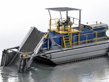 Amphibious weed harvester collecting aquatic vegetation from a lake and wetland area