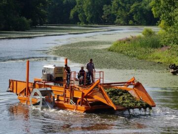 Aquatic weed harvester collecting floating vegetation from a lake surface