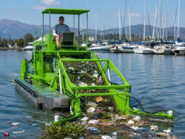 Marina cleaner and trash skimmer collecting floating waste and aquatic debris from harbor water
